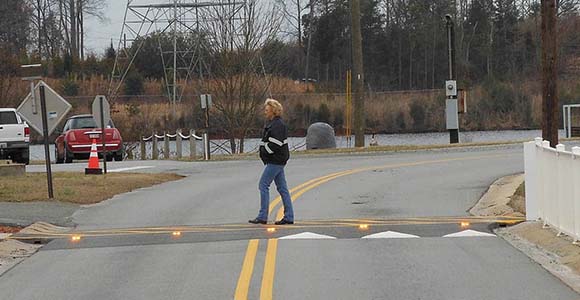 woman crossing crosswalk with in-road LED lights